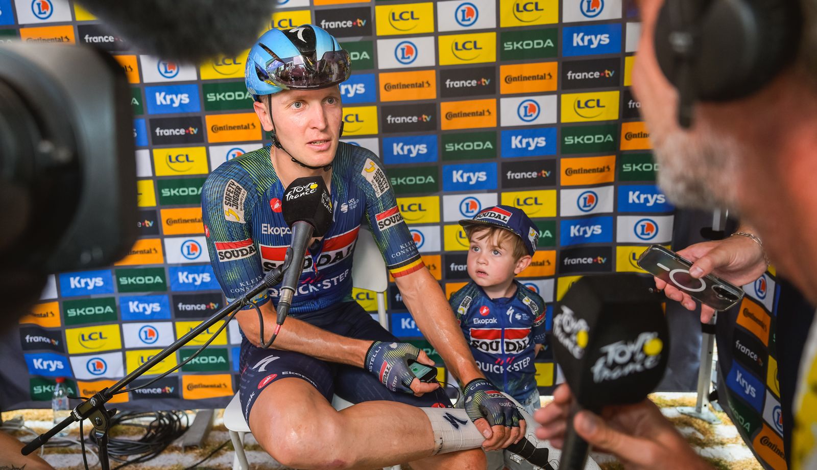 Tim Merlier, junto a su hijo, en la entrevista post-etapa