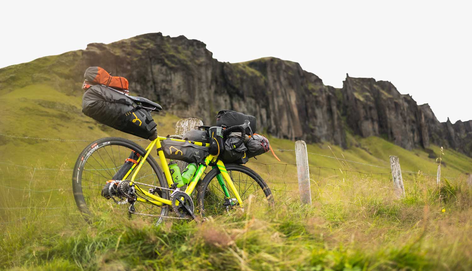 Bicicleta gravel amarilla con alforjas apoyada en valla en Islandia (Foto: Marek Piwnicki)