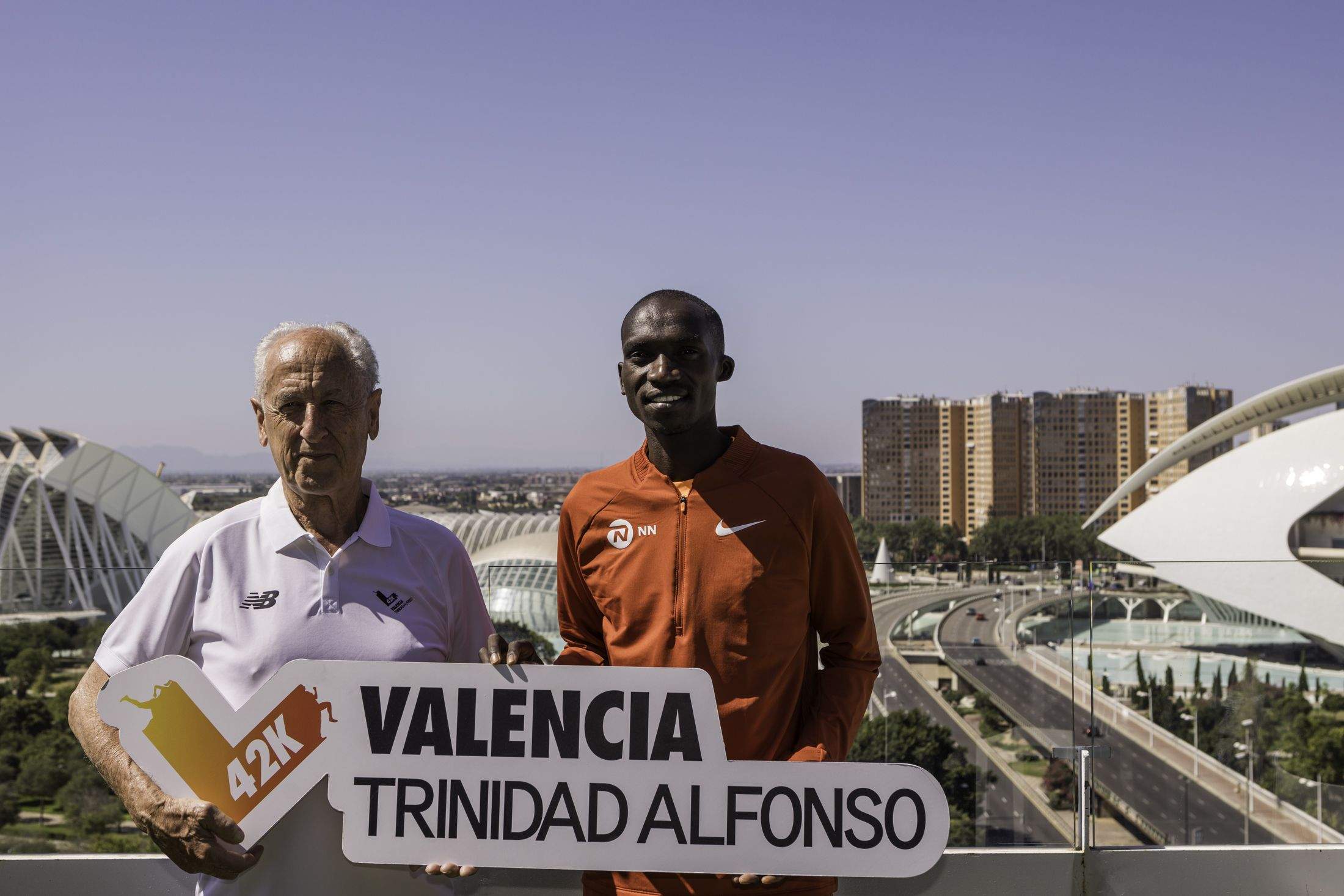 Joshua Cheptegei posando junto a Paco Borao; al fondo, el puente de Monteolivete, lugar de salida del Maratón Valencia Trinidad Alfonso. TONI MARÍN