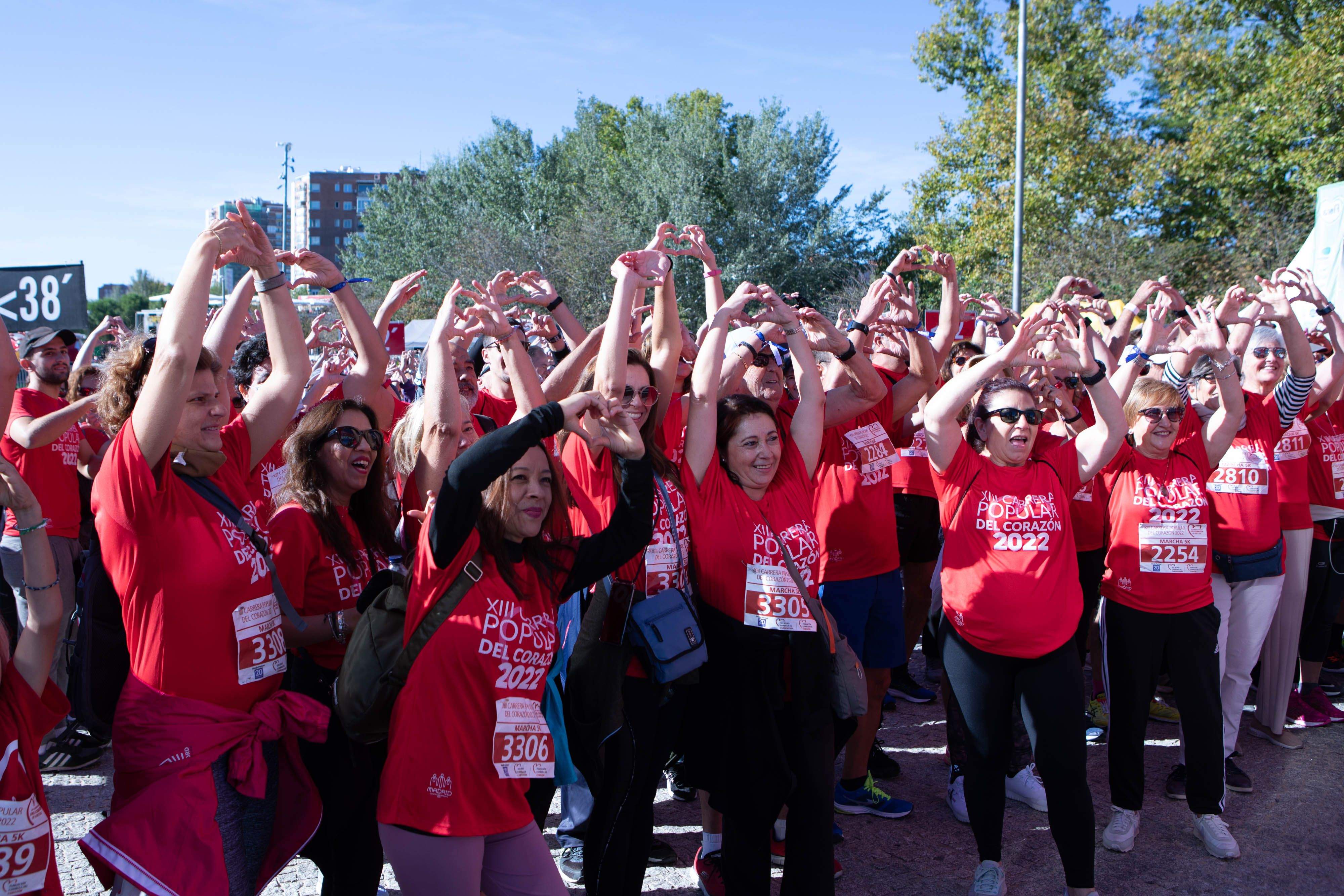 Participantes de la marcha de 4,5 kilómetros de la Carrera Popular del Corazón simulando con sus brazos el músculo que da nombre a la prueba.