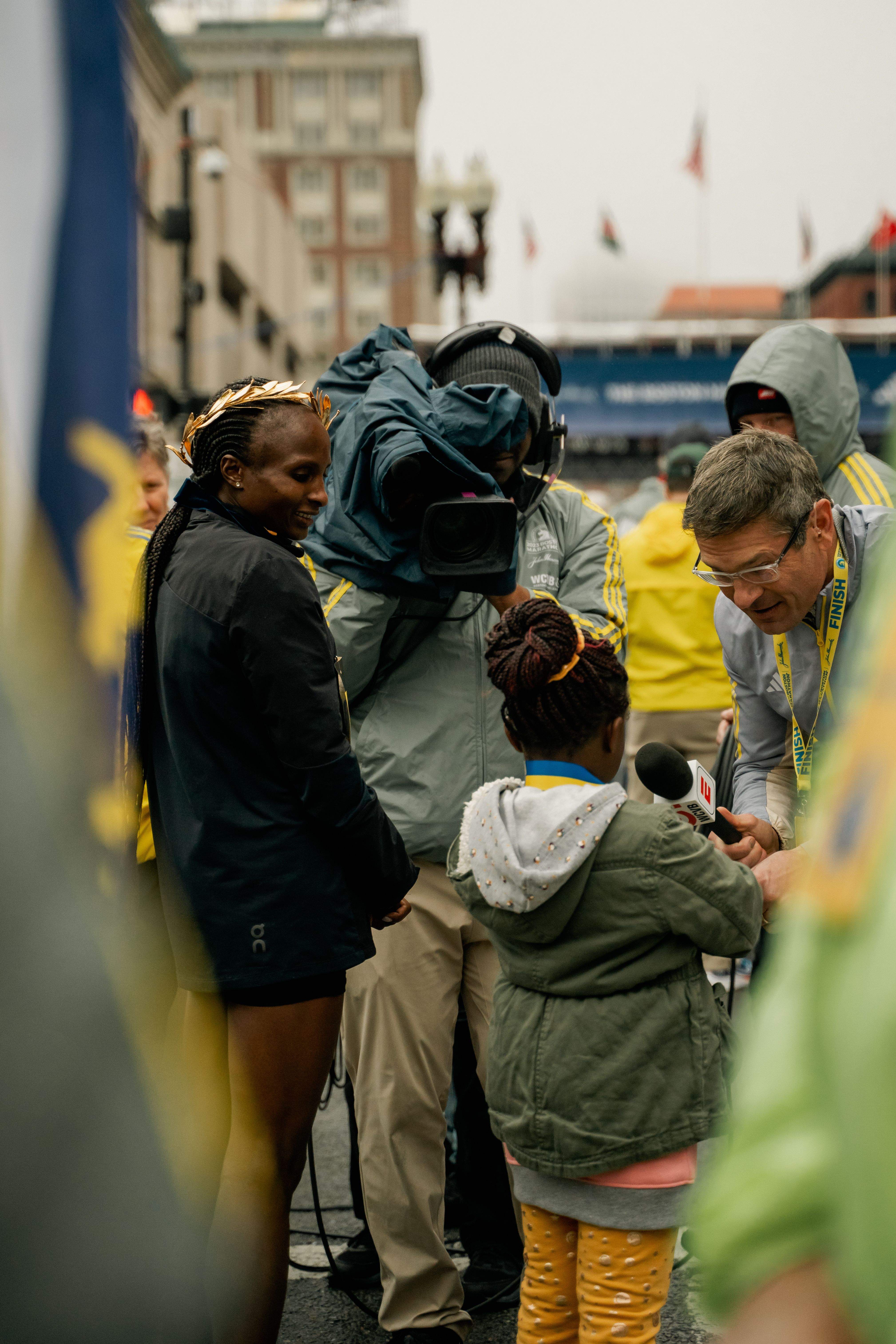 Obiri mira a su hija Tanya, entrevistada por la prensa, después de su victoria en el Maratón de Boston 2023. OAC.