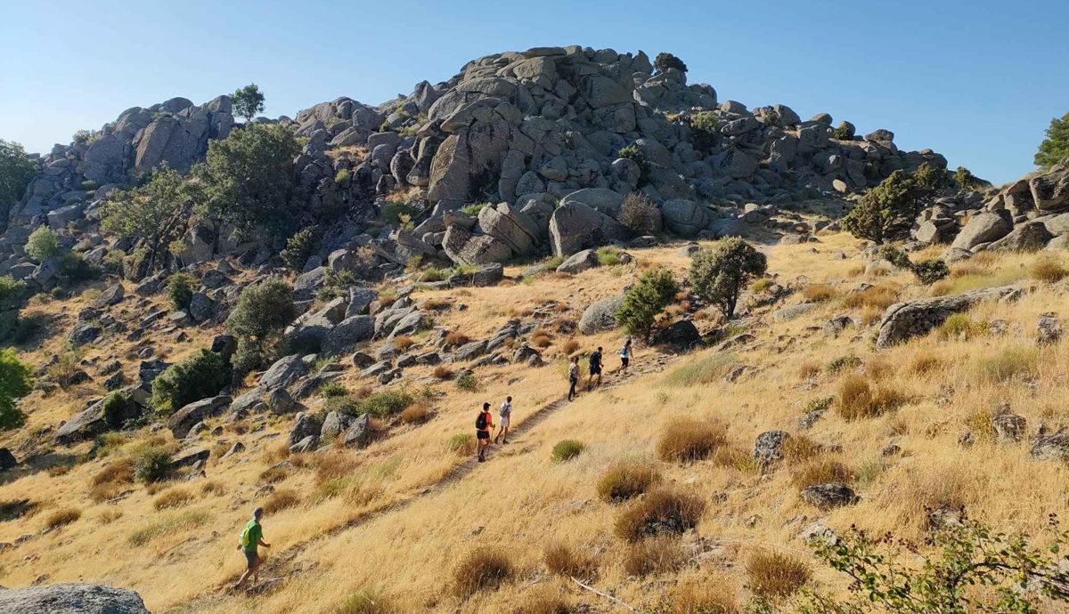 Participantes de la travesía de las cumbres Escurialenses 2022 llegando al collado de Entrecabezas, con El Escorial a un lado y Zarzalejo al otro