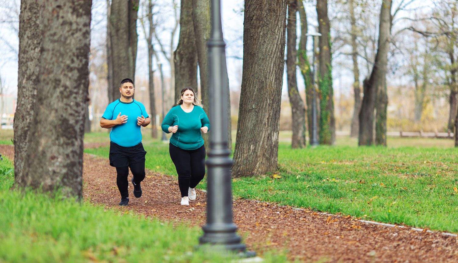 Dos personas con sobrepeso corriendo en el parque. Foto: iStock