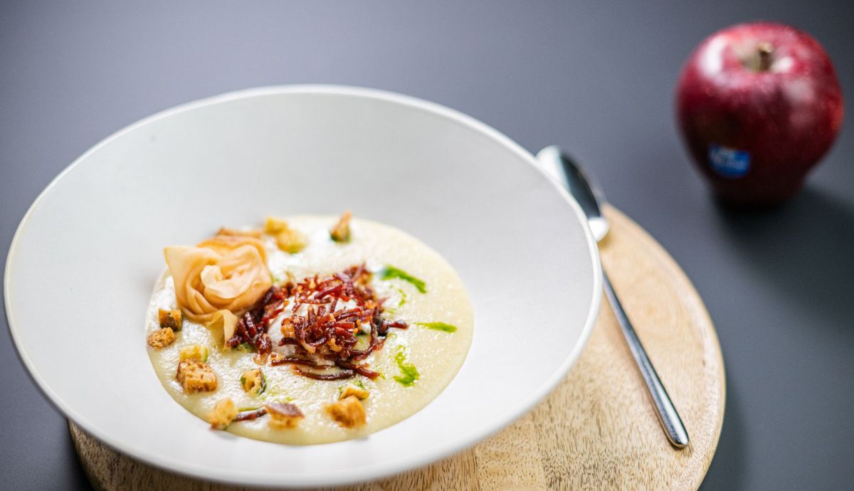 Receta de crema de Red Deliciuous Marlene® y apio con huevo escalfado, tiras de jamón y flor de manzano Receta de crema de Red Deliciuous Marlene® y apio con huevo escalfado, tiras de jamón y flor de manzano