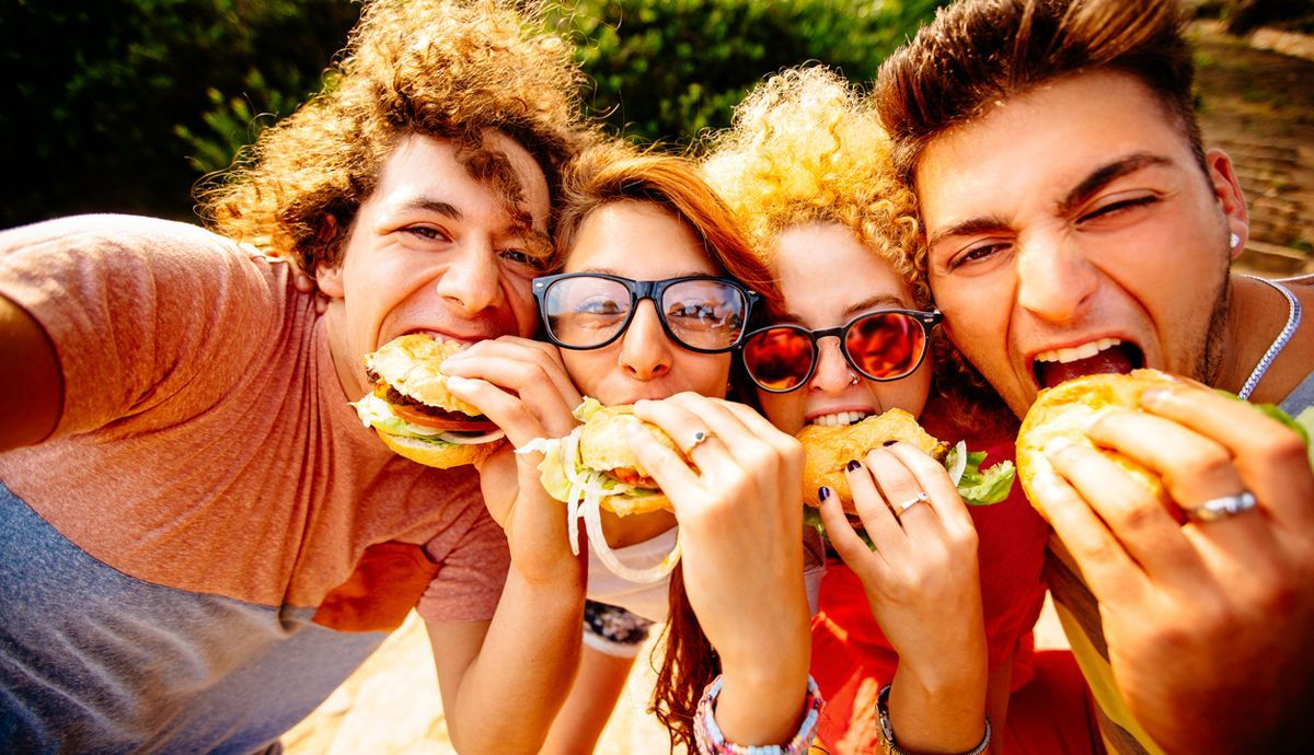 Jóvenes comiendo comida basura, perjudicial para la microbiota Jóvenes comiendo comida basura, perjudicial para la microbiota